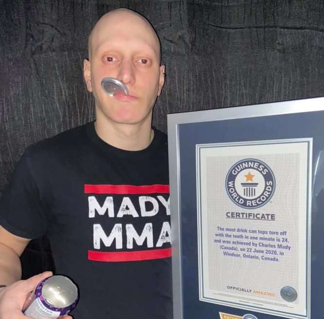 Chucky Mady holding his Guinness World Records certificate for his earlier record of 24 drink can tops torn off with his teeth in one minute