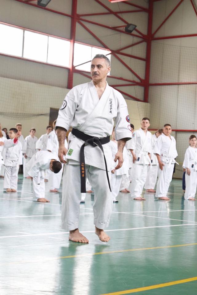 Karate practitioner standing with fellow black belts at a tournament