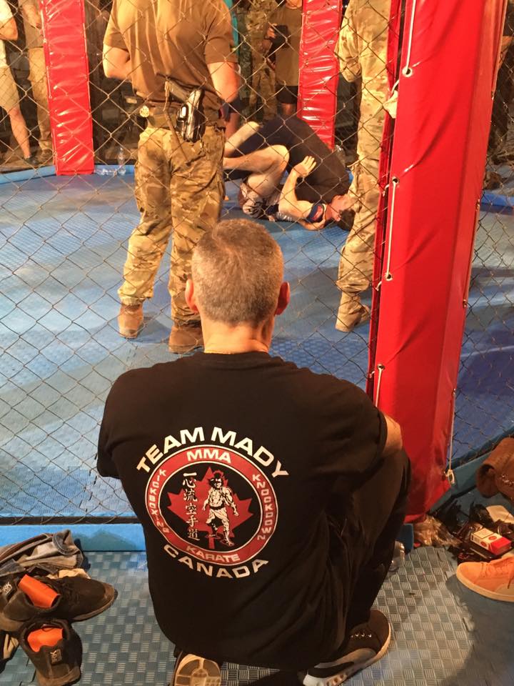 A Team Mady coach watching a bout from beside the cage