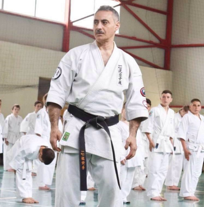 Albert Mady standing in a white gi at a karate event